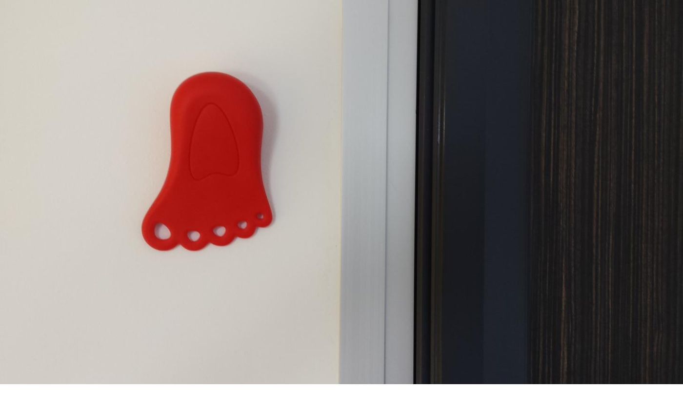 Bloque-porte Finger Alert rouge accroché au mur près d'une porte